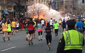 Runners continue to run towards the finish line as an explosion erupts